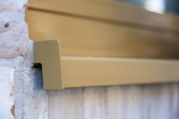 Champagne aluminium vensterbank met zijkapje, close-up op een witgewassen baksteengevel