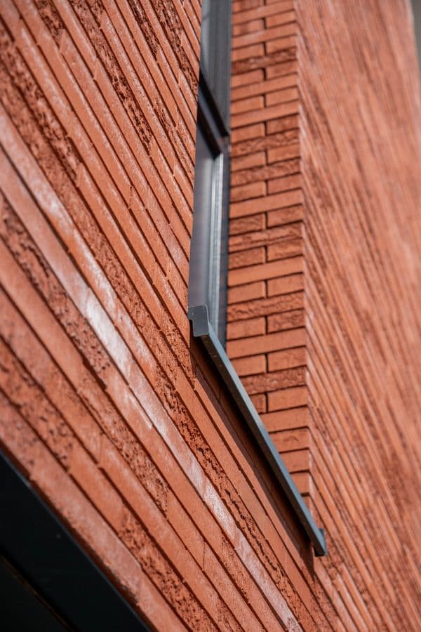 Antraciet aluminium vensterbank op een rode baksteengevel